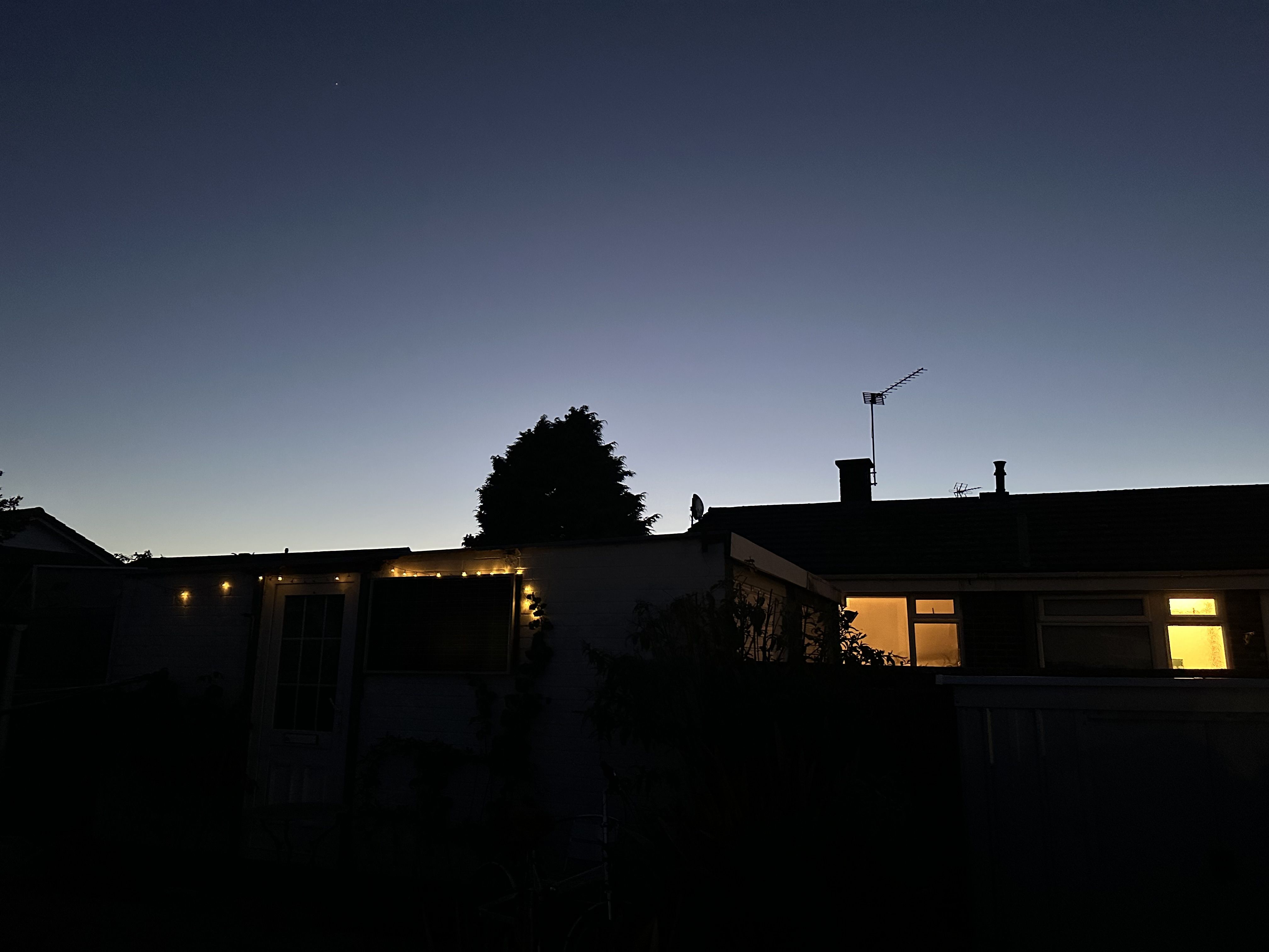 Photo of some fairy lights and lights in windows against a darkening sky